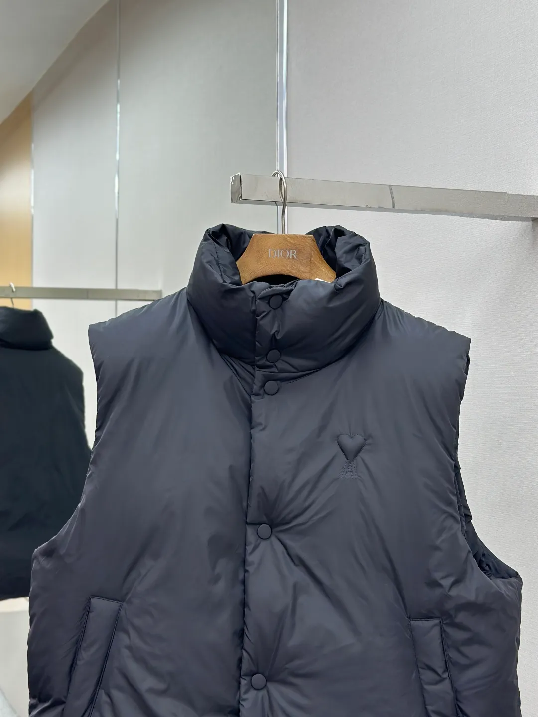P810 AMIPARIS love padded embroidered down vest Fabric selection: Taffeta fabric woven from 100% polyester fiber. It adopts warp and weft plain weave and is woven very tightly, making the surface of the fabric extremely smooth and flat, with a "skinny" and stiffness that is not easy to collapse. When rubbed or moved around, it will make a unique, crisp "rustling" sound. At the same time, it has a delicate plain texture and a soft, elegant silky luster. This kind of luster is not as dazzling as satin, but more restrained and advanced.  Lining selection: Use 100% nylon to create the lining. The high-density and tight weaving process prevents tiny lint from getting out of the gaps in the fabric. The smooth surface improves the putting on and taking off experience, and the excellent wear and tear resistance ensures damage caused by frequent use, while the light and soft texture does not affect the overall weight.  Technology: The fabric and padding material are tightly fixed on the frame of the embroidery machine. The embroidery machine uses sparse stitches along the padding layer to outline the filling area of the pattern, and then runs the overlay layer's padding, using dense stitches to perfectly cover the foam padding layer, thus forming a slightly raised love embroidery, which feels soft and full, enhancing recognition while maintaining a low profile. High-quality filling: It uses 90 white duck down with a weight of 160g to ensure excellent thermal insulation performance. After strict screening and processing, the velvet is not easy to get drilled, ensuring durability.  Accessories: One-to-one customized three-standard, one-to-one customized hem elastic buckle, one-to-one customized snap button SIZE: XS S M L